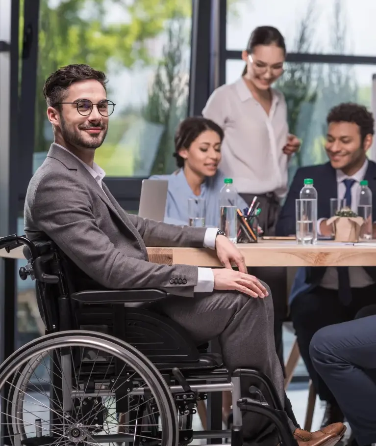 Diverse Teammitglieder arbeiten zusammen im Büro, darunter eine Person im Rollstuhl.