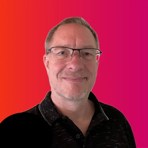 Porträt von Gordon Wenk, freiberuflicher IT-Berater und Softwareentwickler, vor einem verlaufenden pink-roten Hintergrund. Er trägt eine Brille und ein dunkles Polo-Shirt und lächelt freundlich.